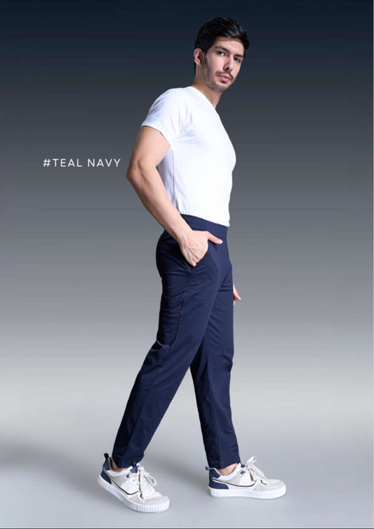 Man wearing a white t-shirt and navy pants with white sneakers on a gray background